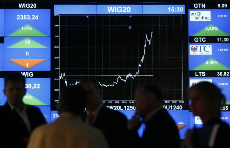 © Reuters. People talk in front of a screen showing the Polish stock market index (WIG20) at the Warsaw Stock Exchange