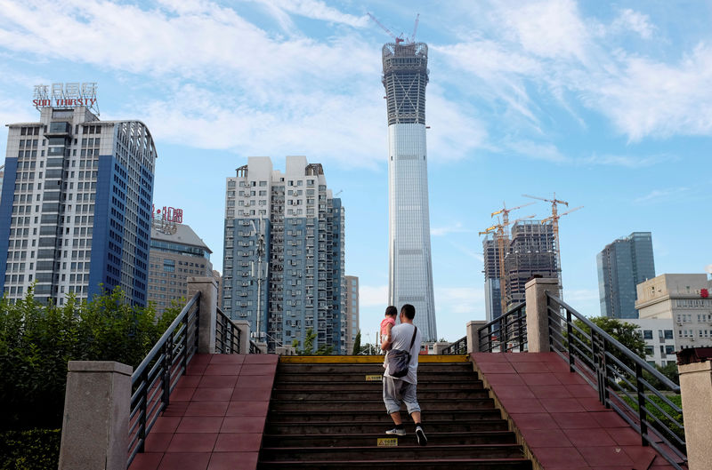 © Reuters. FILE PHOTO: A man carrying a girl walks through a bridge at a park next to Beijing's central business area