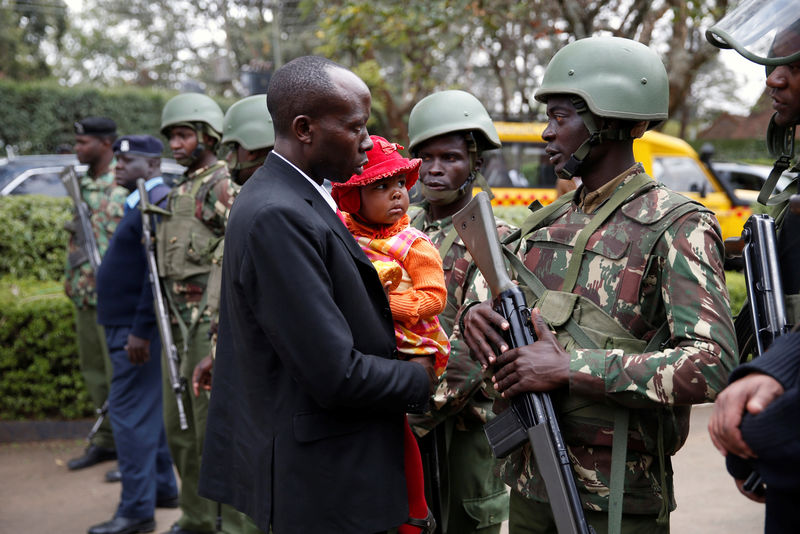 © Reuters. Kenyan police officers prevent a relative from entering the scene where seven Kenyan teenage schoolgirls died and 10 more were hospitalized after a fire engulfed their boarding school dormitory in Nairobi