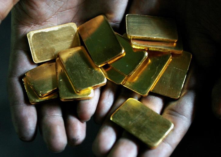 © Reuters. FILE PHOTO: A worker shows gold biscuits at a precious metals refinery in Mumbai