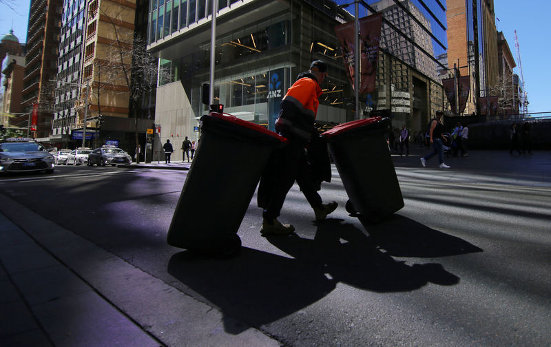 © Reuters. A sanitation worker walks across a street with bins  in Sydney, Australia