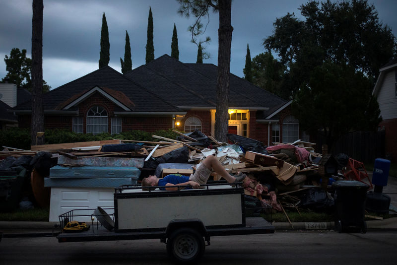 © Reuters. A boy lies on furniture on back of trailer while passing debris from the house flooded by Tropical Storm Harvey in Houston