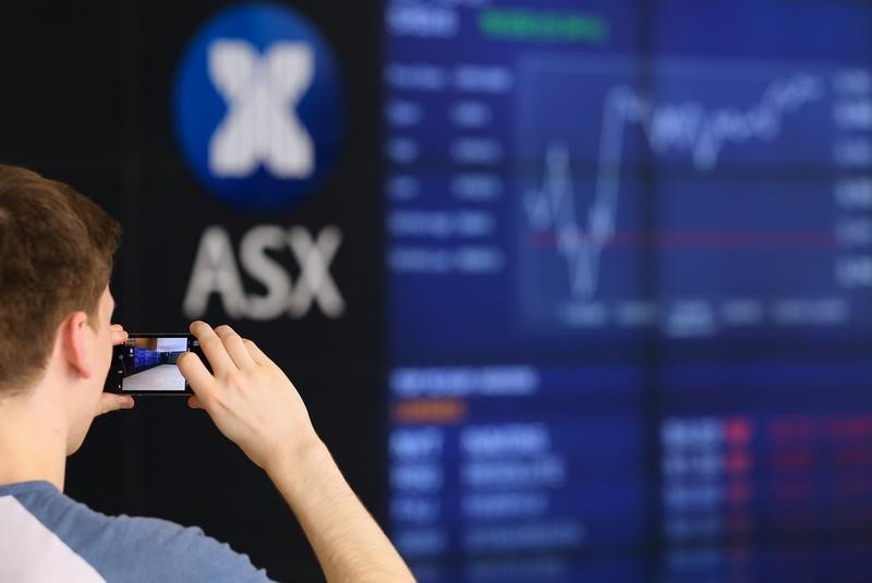 © Reuters. FILE PHOTO: A visitor takes a photograph of a board displaying stock prices at the Australian Securities Exchange (ASX) in Sydney