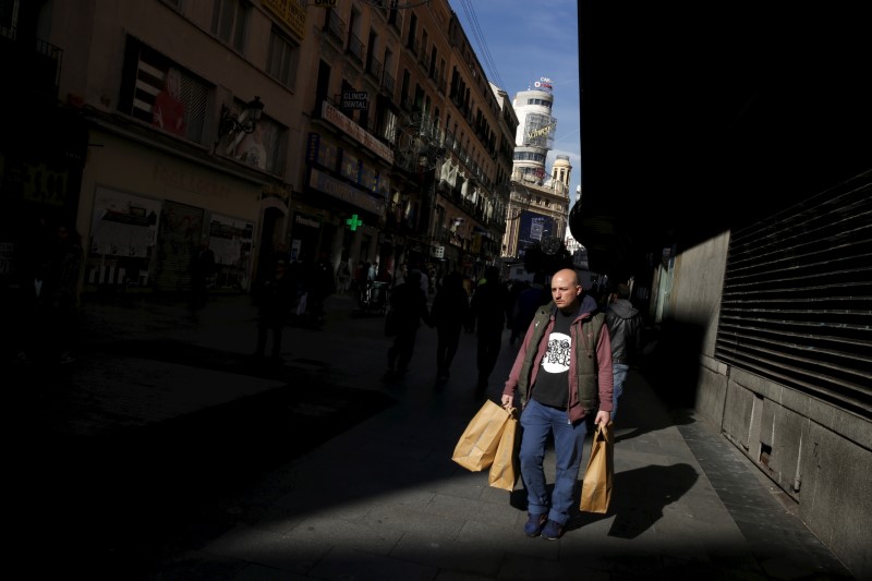 © Reuters. A man carries shopping bags in a shopping district in downtown Madrid