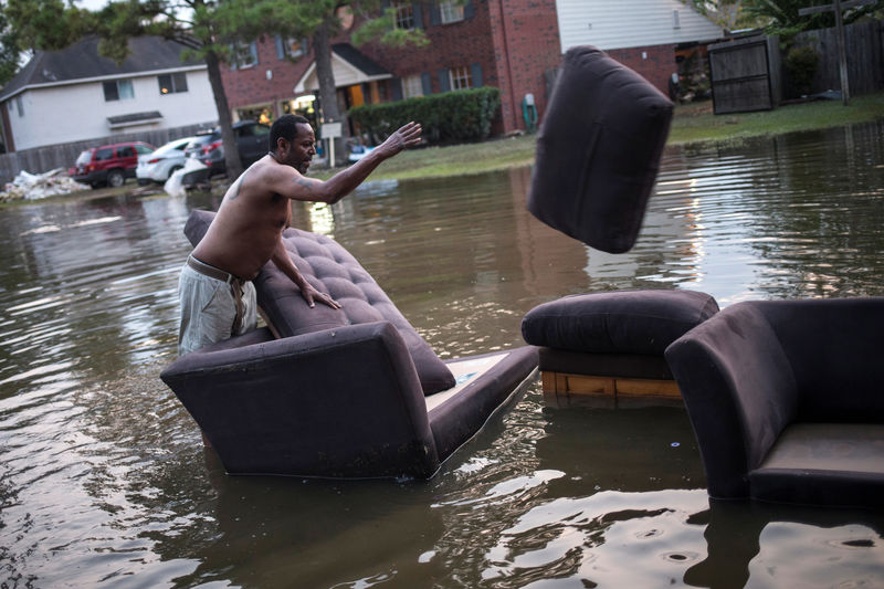 © Reuters. Man moves sofas onto the sidewalk from his house which was left flooded from Tropical Storm Harvey in Houston, Texas