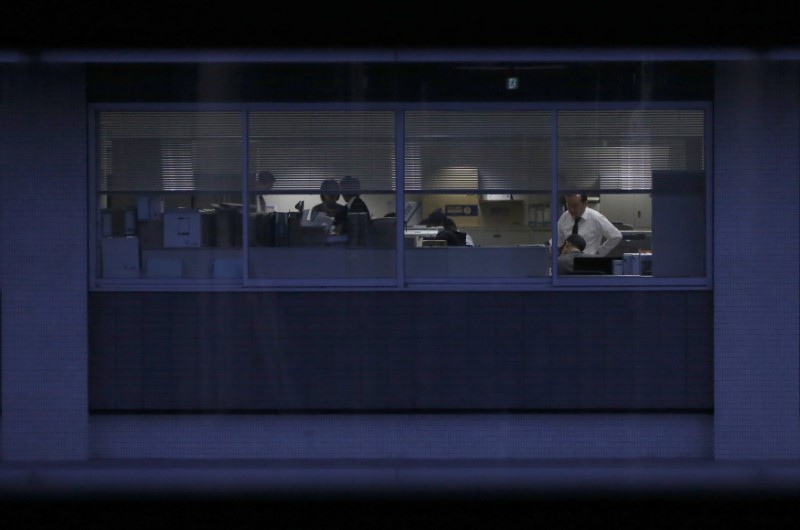 © Reuters. Officer workers are pictured through a building window during dusk in Tokyo