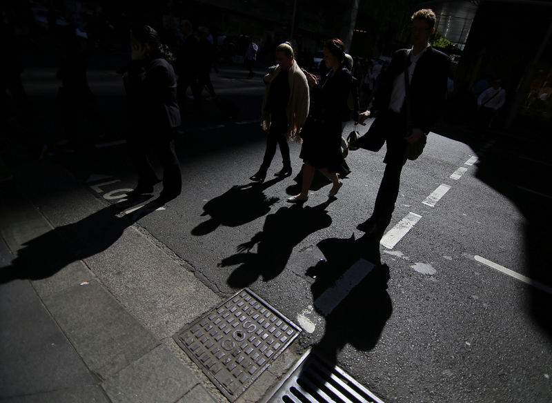 © Reuters. Office workers cross a street in Sydney