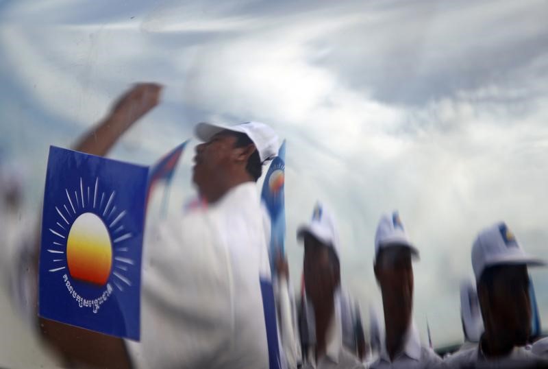 © Reuters. FILE PHOTO: Supporters of the Cambodia National Rescue Party are reflected in the body of a car as they attend a local election campaign in Phnom Penh