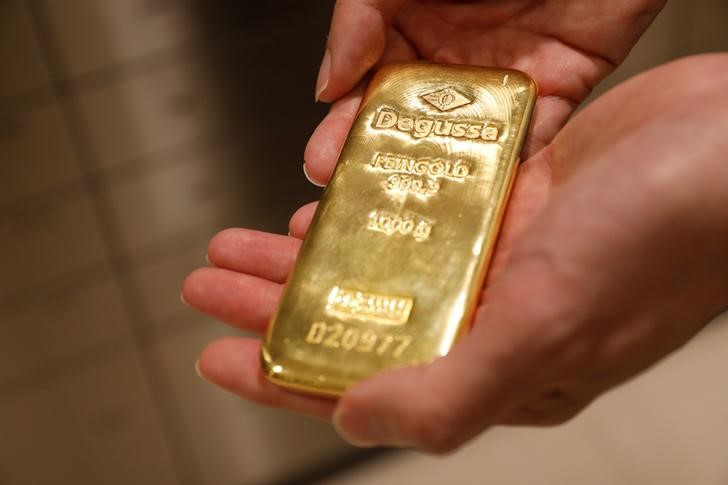 © Reuters. Сотрудник магазина Degussa в Сингапуре демонстрирует золотой слиток