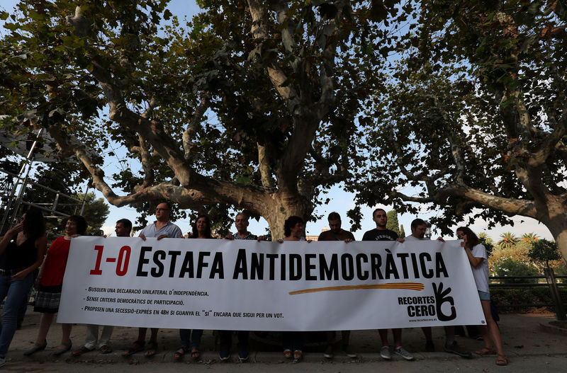 © Reuters. Anti-indenpendece supporters holds a banner in front of the Catalonian regional Parliament in Barcelona