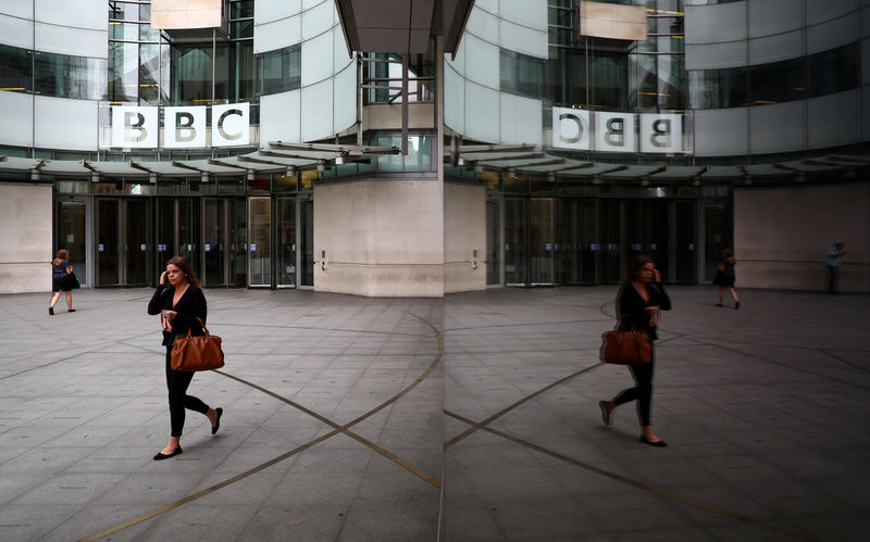 © Reuters. FILE PHOTO: A woman is reflected as she passes the BBC's Broadcasting House in London