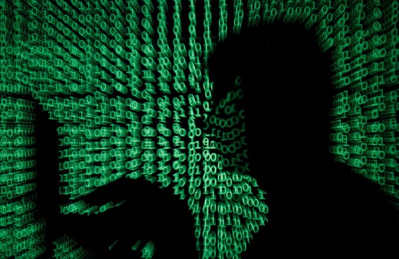 © Reuters. FILE PHOTO: Man holds laptop computer as cyber code is projected on him in this illustration picture