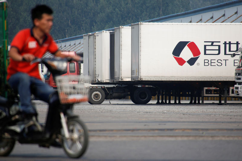 © Reuters. FILE PHOTO - A man rides an electric scooter past a distribution hub of the Chinese logistics company Best Inc in Beijing
