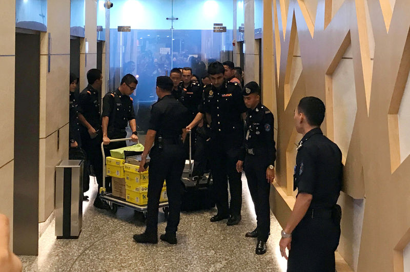 © Reuters. FILE PHOTO: Policemen escort a trolley of documents seized by the Malaysian Anti-Corruption Commission at the Felda Global Ventures Holdings headquarters, in Kuala Lumpur