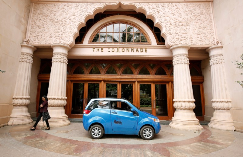 © Reuters. A woman walks past a Mahindra e2o electric car during a media preview in Bengaluru