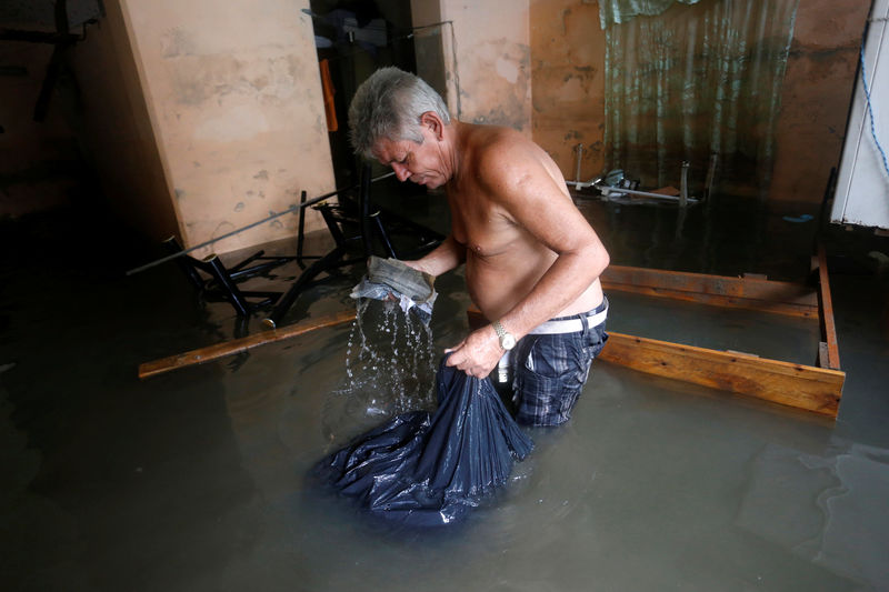 © Reuters. A man picks up spoiled things in his flooded home, after  the passing of Hurricane Irma, in Havana