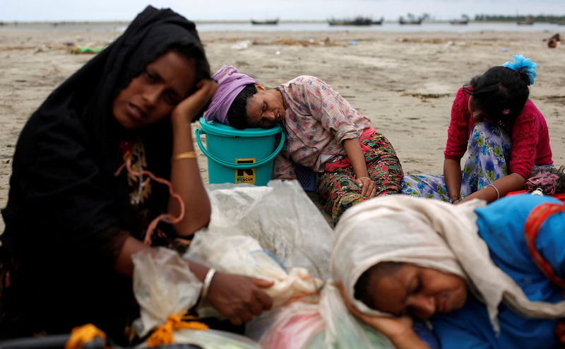 © Reuters. Exhausted Rohingya refugees rest on the shore after crossing the Bangladesh-Myanmar border by boat through the Bay of Bengal in Shah Porir Dwip