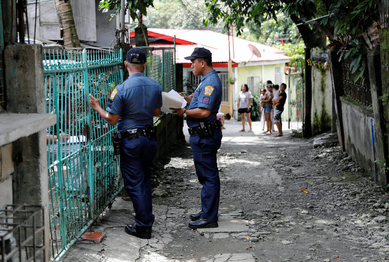 © Reuters. Policemen knock door to door and interview residents during a drug testing operation in Payatas, Quezon City, Metro Manila