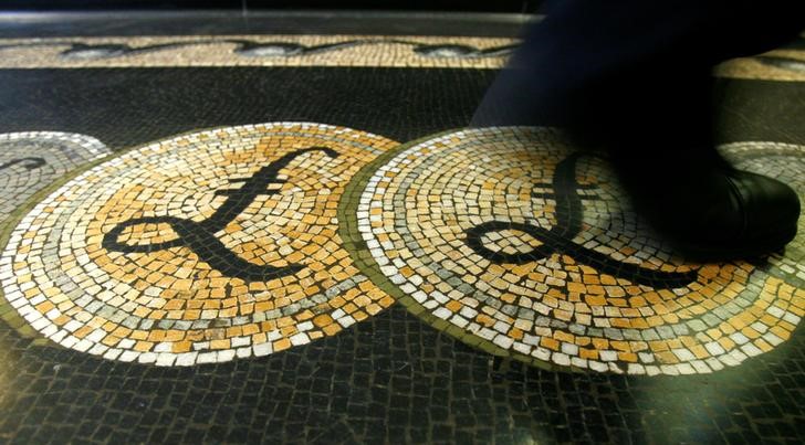 © Reuters. FILE PHOTO: A person walks over a mosaic depicting pound sterling symbols