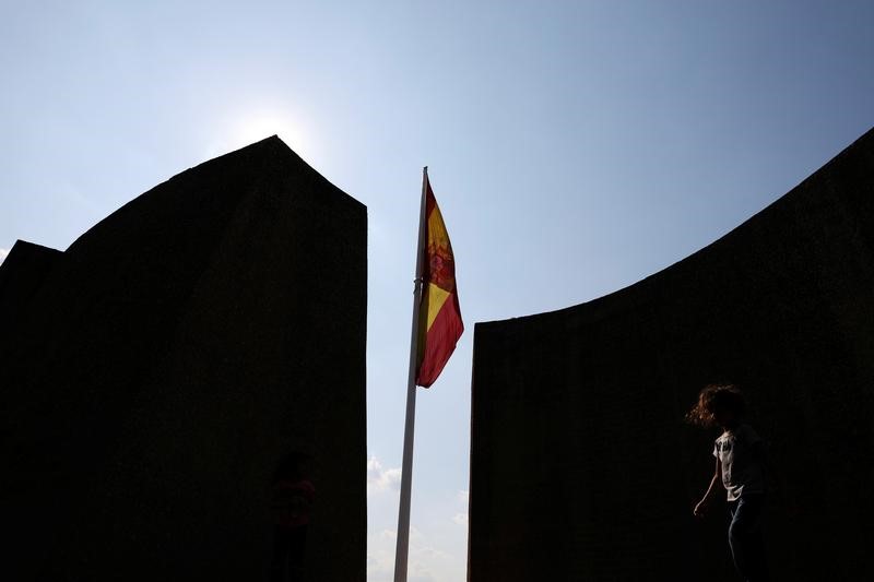 © Reuters. A child walks by a Spanish flag in Plaza Colon in Madrid