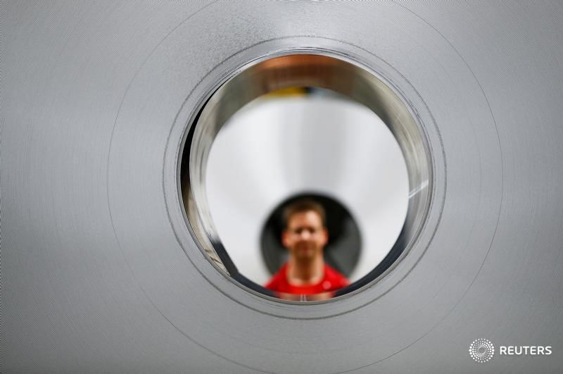 © Reuters. A worker poses for a photo through an aluminium coil during opening of a production line for the car industry at a branch of Norway's Hydro aluminum company in Grevenbroich