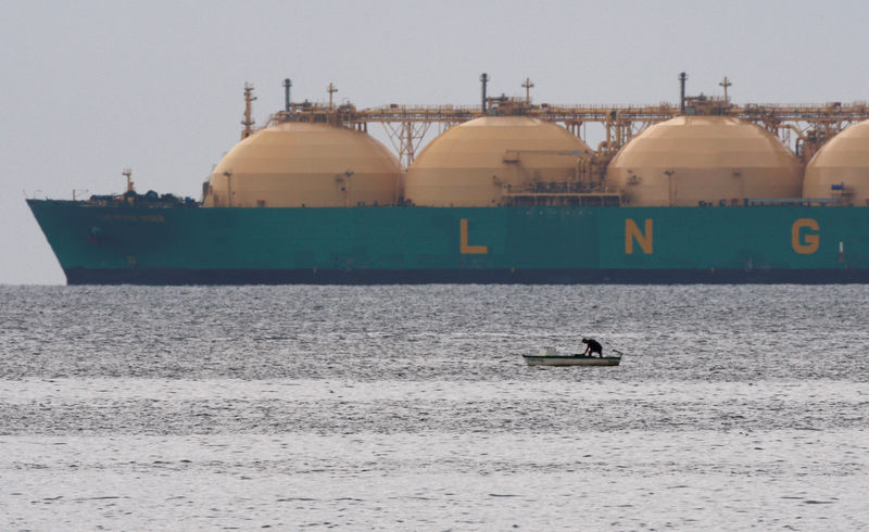 © Reuters. FILE PHOTO: Fisherman stands in boat as a liquefied natural gas tanker passes the coast near Havana