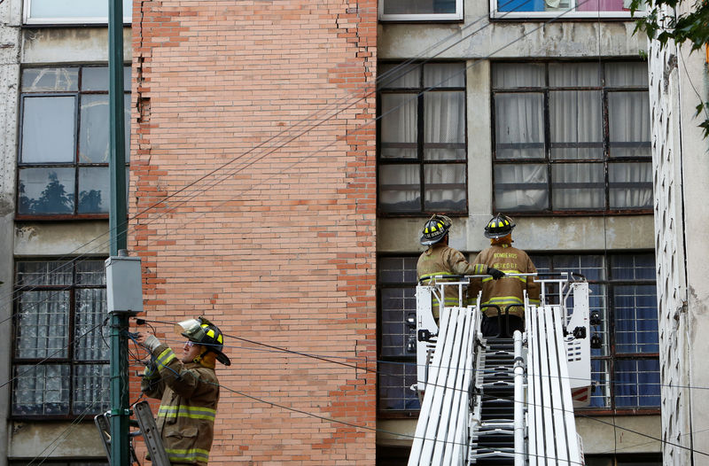 © Reuters. Firefighters stand outside a building damaged by an earthquake that struck off the southern coast of Mexico late on Thursday, in Mexico City