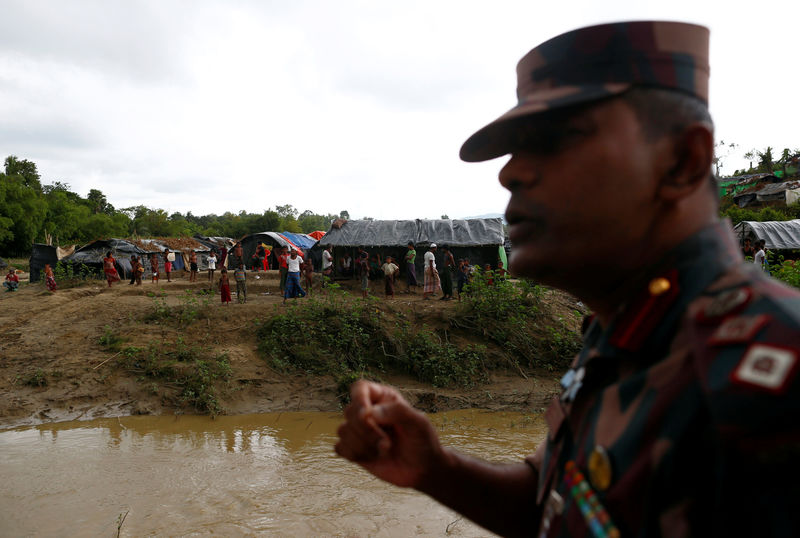 © Reuters. Lt Col Khan, a commanding officer of the Border Guards Bangladesh, speaks as Rohingya refugees stand outside their temporary shelters at no man's land between Bangladesh-Myanmar border, in Cox's Bazar