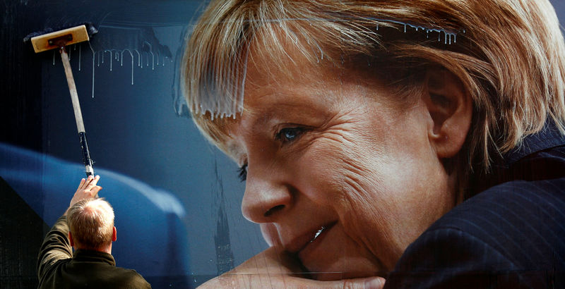 © Reuters. Worker pastes up an election campaign poster for the upcoming general elections of the CDU party with a headshot of Merkel in Berlin