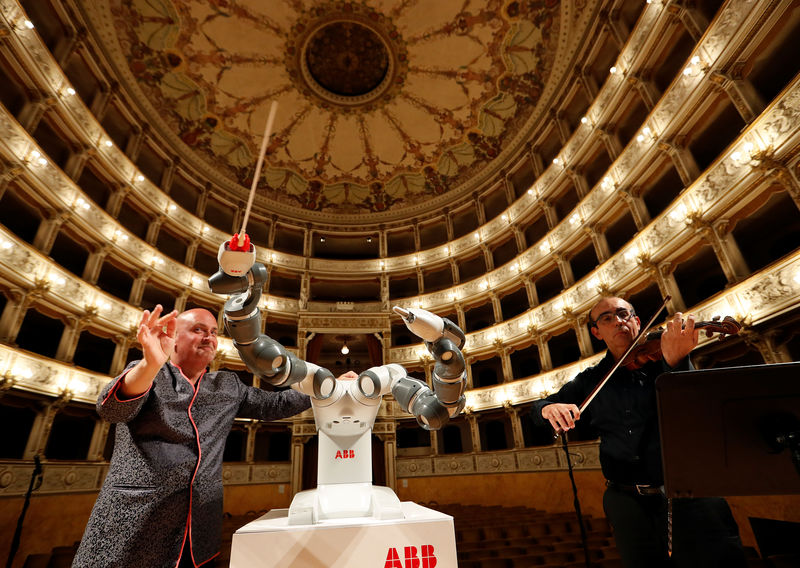 © Reuters. Colombini, trainer of robot YuMi and orchestra leader and first violinist Cavalieri during the rehearsal at Verdi Theatre in Pisa