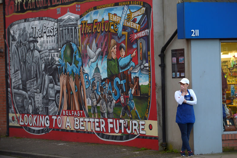 © Reuters. A woman stands beside a mural in a loyalist area of Belfast