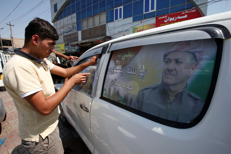 © Reuters. A Kurdish man decorates a car with a poster bearing the image of Iraq's Kurdistan region's President Massoud Barzani, urging people to vote in the September 25th independence referendum, in Erbil