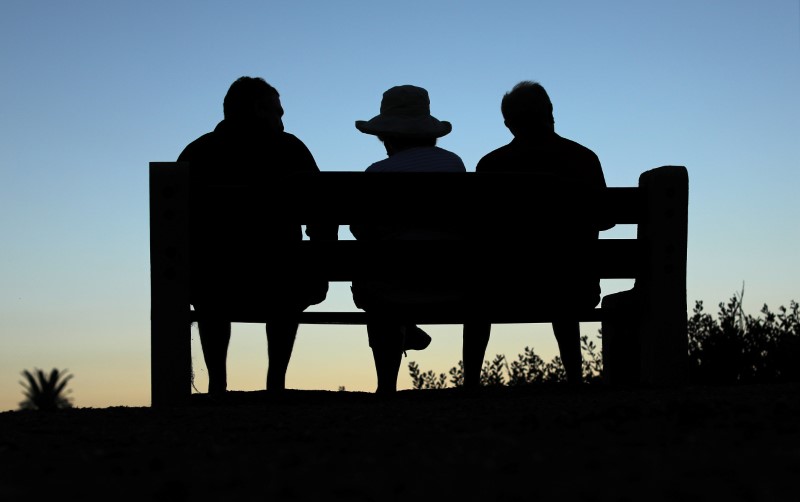 © Reuters. Elderly people sit on a park bench after sun set in Encinitas