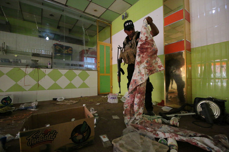 © Reuters. Agente de segurança inspeciona local de ataque em restaurante na cidade iraquiana de Nassiriya