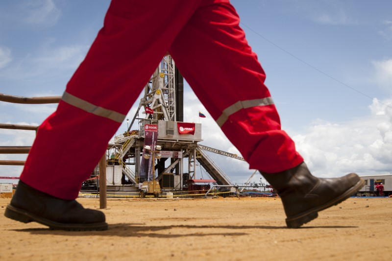 © Reuters. FILE PHOTO: An oil worker walks past a drilling rig at an oil well operated by Venezuela's state oil company PDVSA in Morichal July 28, 2011