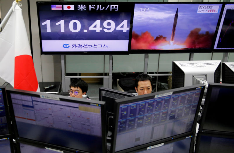 © Reuters. FILE PHOTO: Employees of a foreign exchange trading company work in front of monitors showing TV news on North Korea's threat and the Japanese yen's exchange rate against the U.S. dollar in Tokyo