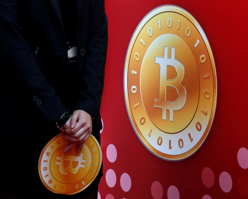 © Reuters. FILE PHOTO: Attendant holds bitcoin sign during the opening of Hong Kong's first bitcoin retail store