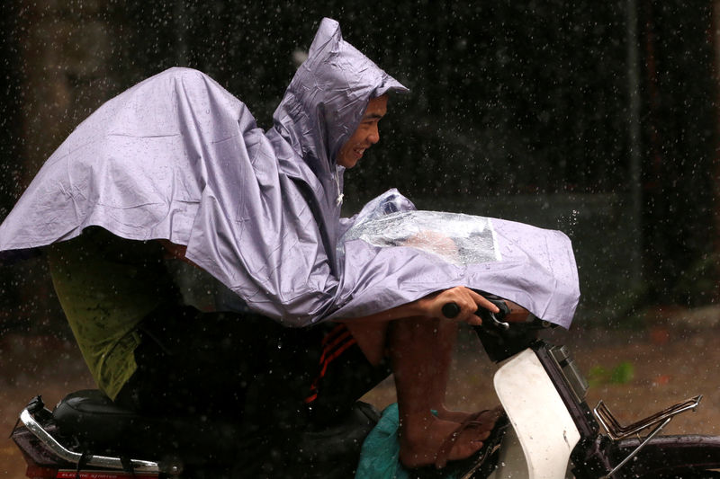 © Reuters. People ride a motorbike while the Doksuri storm hits in Ha Tinh province, Vietnam