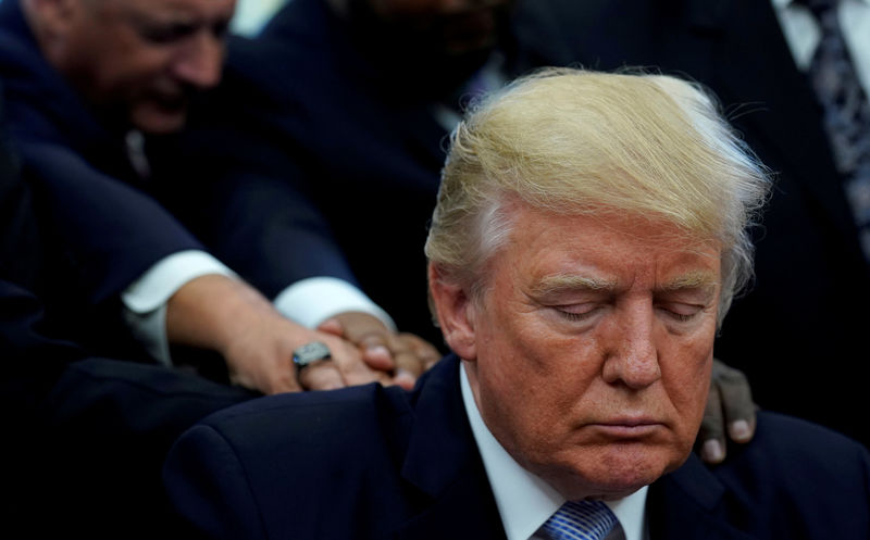 © Reuters. FILE PHOTO: Faith leaders place their hands on the shoulders of U.S. President Trump as he takes part in a prayer for those affected by Hurricane Harvey in the Oval Office of the White House in Washington