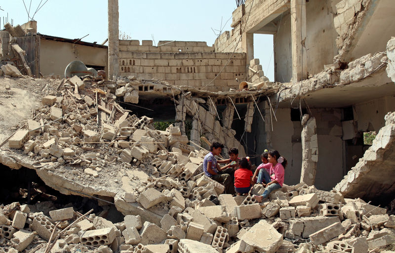 © Reuters. Children sit together at a damaged site at a rebel-held area in Deraa