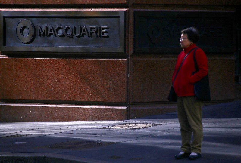 © Reuters. A pedestrian stands near the logo of Australia's biggest investment bank Macquarie Group Ltd which adorns a wall on the outside of their Sydney office headquarters in central Sydney, Australia
