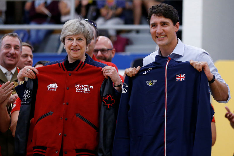 © Reuters. Britain's PM May and Canada's PM Trudeau hold up team jackets after exchanging them during an Invictus Games event in Ottawa