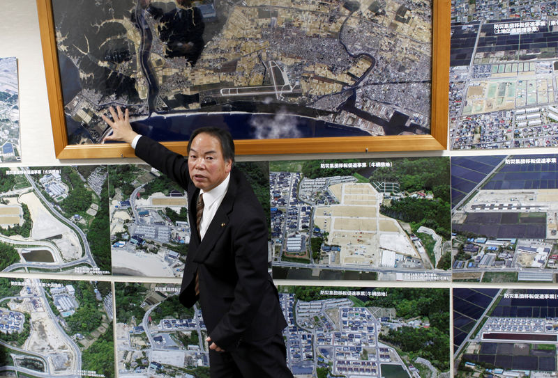 © Reuters. Higashi-Matsushima city major Hideo Abe shows off pictures of the city's reconstructing plan after an earthquake and tsunami disaster, at the city government office in Higashi-Matsushima