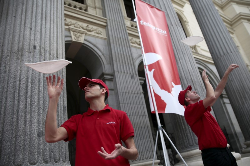 © Reuters. FILE PHOTO - Men throw pizza doughs into the air in front of the bourse during Telepizza's bourse debut in Madrid