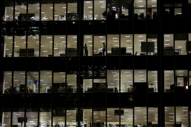 © Reuters. FILE PHOTO: Workers are seen in office windows in the financial district of Canary Wharf in London