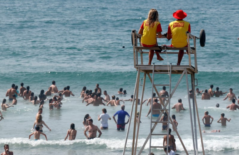 © Reuters. Lifeguards watch as people enjoy the sun and the seawater during a summer day in Biarritz
