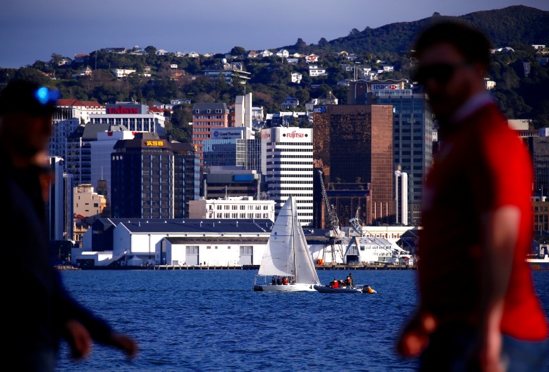 © Reuters. FILE PHOTO: Pedestrians walk past a sailing boat as it passes in front of the central business district of Wellington in New Zealand