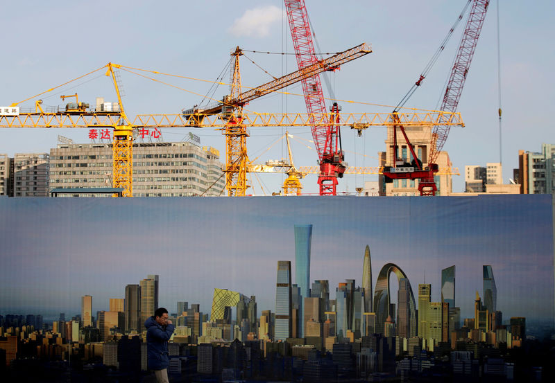 © Reuters. FILE PHOTO: A man walks past the hoarding of a construction site in Beijing