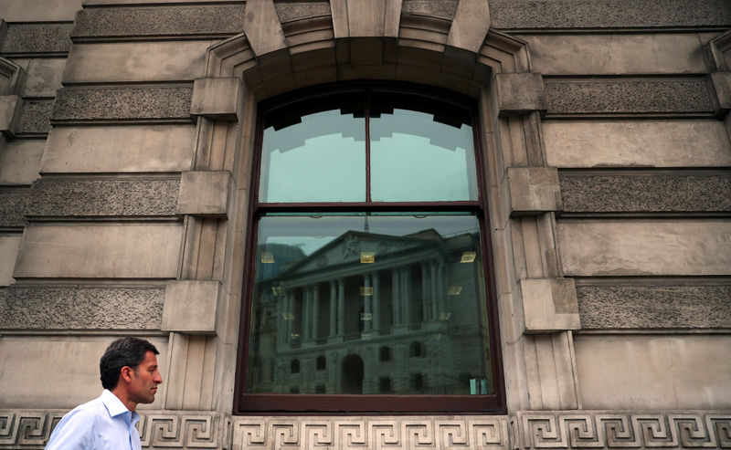 © Reuters. A man walks past a reflection of the Bank of England in a window in the City of London
