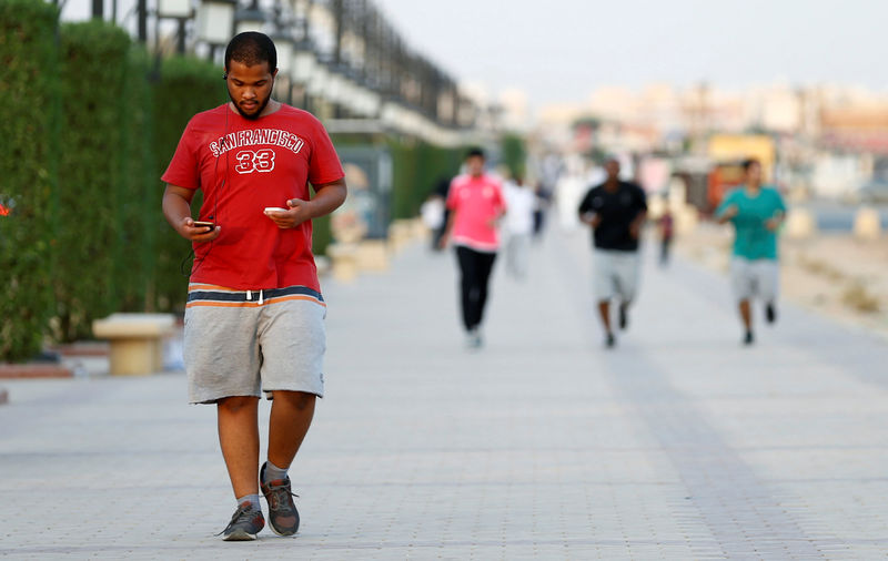 © Reuters. A Saudi man uses his smartphone as he walks on a sidewalk in Riyadh